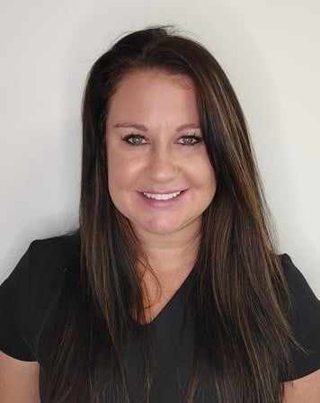 Morgan Tucker, Licensed Aesthetician, smiling in black scrubs